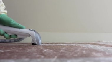 Bir kişi ev ortamında halıyı tazelemek için temizlik aracı kullanır.