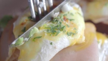 Bitkilerle kaplı taze haşlanmış yumurta çatal ve bıçakla kesiliyor..