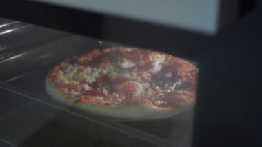Lezzetli bir pizza yavaşça pişirir, mutfağı aromasıyla doldurur..