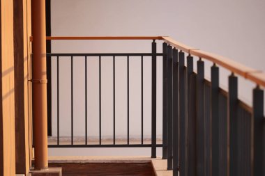 Güneş ışığı, korkuluklu bir balkonun ahşap zeminini aydınlatır..