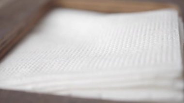 Düzenli beyaz peçeteler ahşap bir kabın içinde sergilenir..