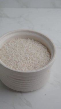 Mermer tezgaha yerleştirilmiş pişmemiş pirinçle dolu bir kase.