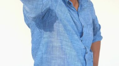 Bir adamın mavi gömleğinde belirgin bir ter vardır, parlak bir noktada..