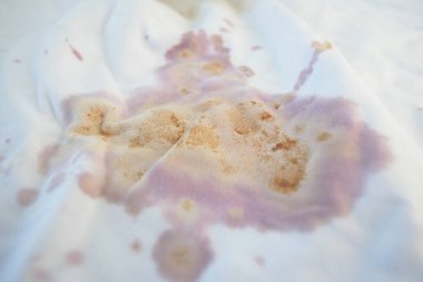 A piece of white fabric shows multiple color stains and spots.
