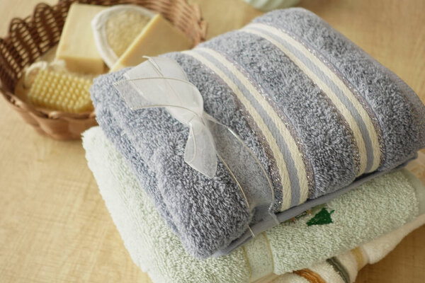 Neatly stacked towels with a decorative ribbon and natural soaps are displayed.