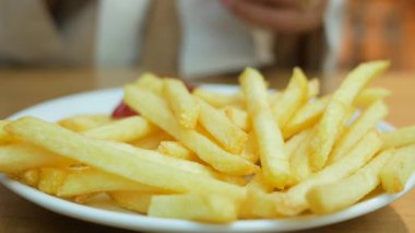 Yeni hazırlanmış patates kızartması. Yanında canlı kırmızı bir sos makinesi ile servis ediliyor..