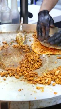 Şef, müşteriler için ısıtmalı büyük bir yüzey üzerinde lezzetli baharatlı et hazırlıyor..