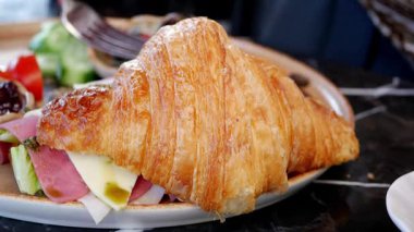 Taze sebzelerin yanında servis edilen gevrek bir kruvasanın içindeki lezzet..