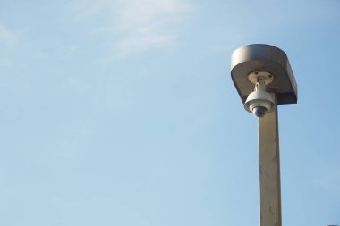 Parlak gökyüzüne karşı bir direğe bir güvenlik kamerası yerleştirildi..