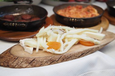 Dilimlenmiş sebze ve peynir, mutfaktaki ahşap bir tahtaya dizilmiş..