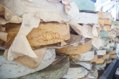 Açık hava pazarında çok çeşitli peynir tekerleri üst üste yığılır..