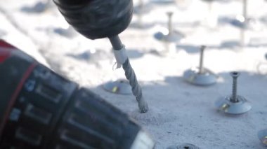 İşçiler dışarıdaki beton yüzeylere delik açmak için elektrikli aletler kullanıyorlar..