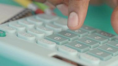 Bir kişi el bilgisayarındaki hesap makinesindeki sayıları hesaplar..