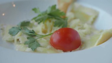 Taze otlar ve domateslerle süslenmiş güzel bir tabak makarna..