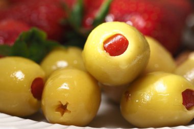 Beyaz tabakta kırmızı biberonla doldurulmuş lezzetli yeşil zeytinler..