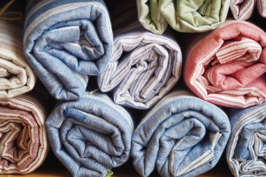 Renkli rulo havlular ahşap bir rafta güzelce dizilmiş..