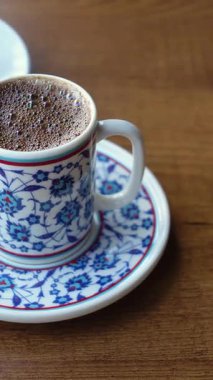 Tahta bir masada, çiçekli güzel bir fincanda Türk kahvesinin tadını çıkarıyorum.,