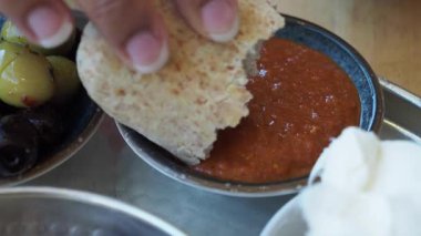 Taze pişmiş ekmek, zeytinli, lezzetli bir sosa batırılır..