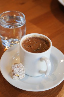Türk kahvesi, tatlı ikram ve sıcak su ile servis edilir.,