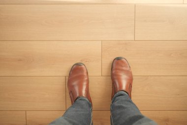 Kahverengi çizmeler, güneş ışığıyla aydınlatılmış pürüzsüz ahşap bir zeminde duruyor..