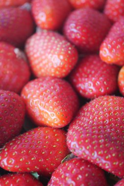 Sulu kırmızı çilekler yerel bir markette üst üste yığılmış, alıcıları davet ediyor..