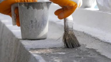 Bir işçi, dışarıdaki beton yapılara ustalıkla son rötuşları yapar..