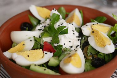 Bir kasede servis edilen yeşiller, yumurtalar ve otlar içeren renkli bir salata..