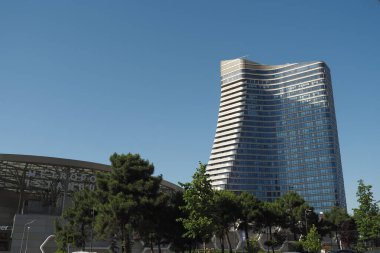 Parlak bir gökdelen, berrak mavi gökyüzüne doğru yükseliyor..