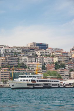 İstanbul 'da hareketli bir kıyı şeridi yakınlarındaki sularda bir feribot geziniyor.