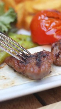 Lezzetli ızgara et canlı sebzelerle eşleştirilir ve sıcak servis edilir..