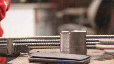 Sanatçılar işlek bir atölyede metal aletler ve malzemelerle çalışırlar..