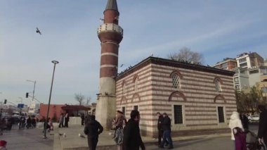 İnsanlar şehir hayatı ve mimarisi ile çevrili eski bir camiyi keşfediyorlar..