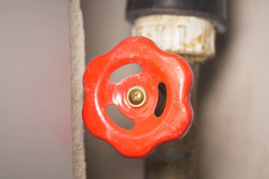 Tesisat ayarları için bir borunun üzerine kırmızı bir vana sapı yerleştiriliyor..