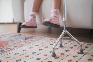 Küçük bir çocuk koltuk değneklerini destek ve rahatlık için kullanır..