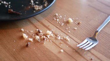 Kalan kırıntılar ve bir çatal öğle yemeğinden sonra ahşap bir masada dinleniyor..