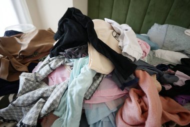 Yatağın üzerine yığılmış giysiler düzensiz bir alan gösteriyor..