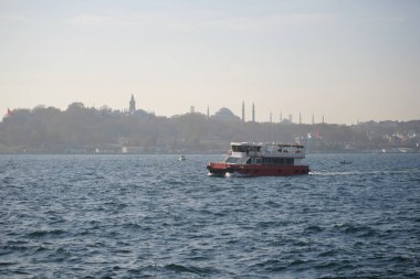 Bir feribot, arka planda İstanbullar 'ın silueti olan Boğaz' ı geçiyor..
