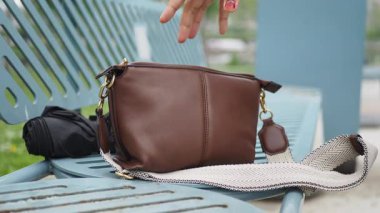 Parktaki mavi bankta bırakılmış kahverengi el çantası. kayıp konsept ,