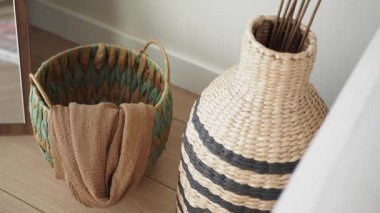 Renkli dokuma sepeti ve çizgili vazo modern bir oda tasarımını tamamlıyor..
