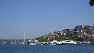 Güneşli bir günde, dalgalı rıhtımı tekneler ve şehir silüetiyle keşfedin..