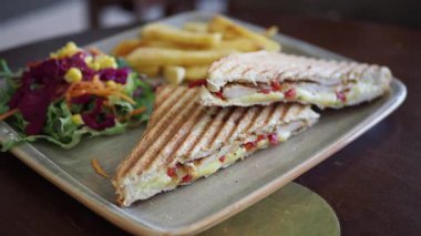 Taze salata ve patates kızartmasıyla birlikte iyi hazırlanmış bir sandviçin tadını çıkarın..