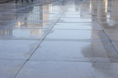 Su damlacıkları güneş ışığında parlak bir mermer yüzeyde parlar..