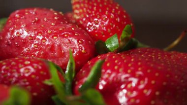 Sulu çilekler ahşap üzerinde dinleniyor, canlı renklerini sergiliyorlar..