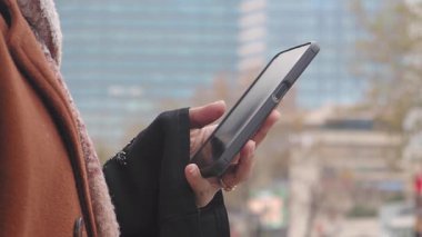 Çevresi şehir binalarıyla çevriliyken bir kişi akıllı telefonla iletişim kuruyor..