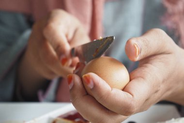 Bir insan kahvaltıda kabuğunu kaynamış yumurtadan dikkatlice çıkarır..