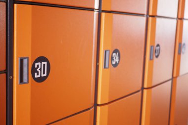 Parlak turuncu depolama dolapları halka açık bir alanda koridor oluşturur..