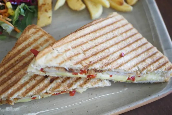 Kızarmış peynir ve biberli sandviç ve yanında patates kızartması..