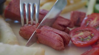 Lezzetli bir yemeği dilimliyor. İçinde domates ve et var. Keyfini çıkarmaya hazır..