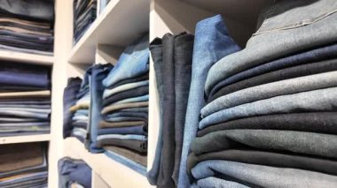 Bir moda mağazasında çeşitli katlanmış kotlar düzenli olarak sergileniyor.