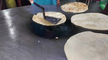Aşçı, yoğun bir markette ızgarada ustalıkla ekmek yapıyor..